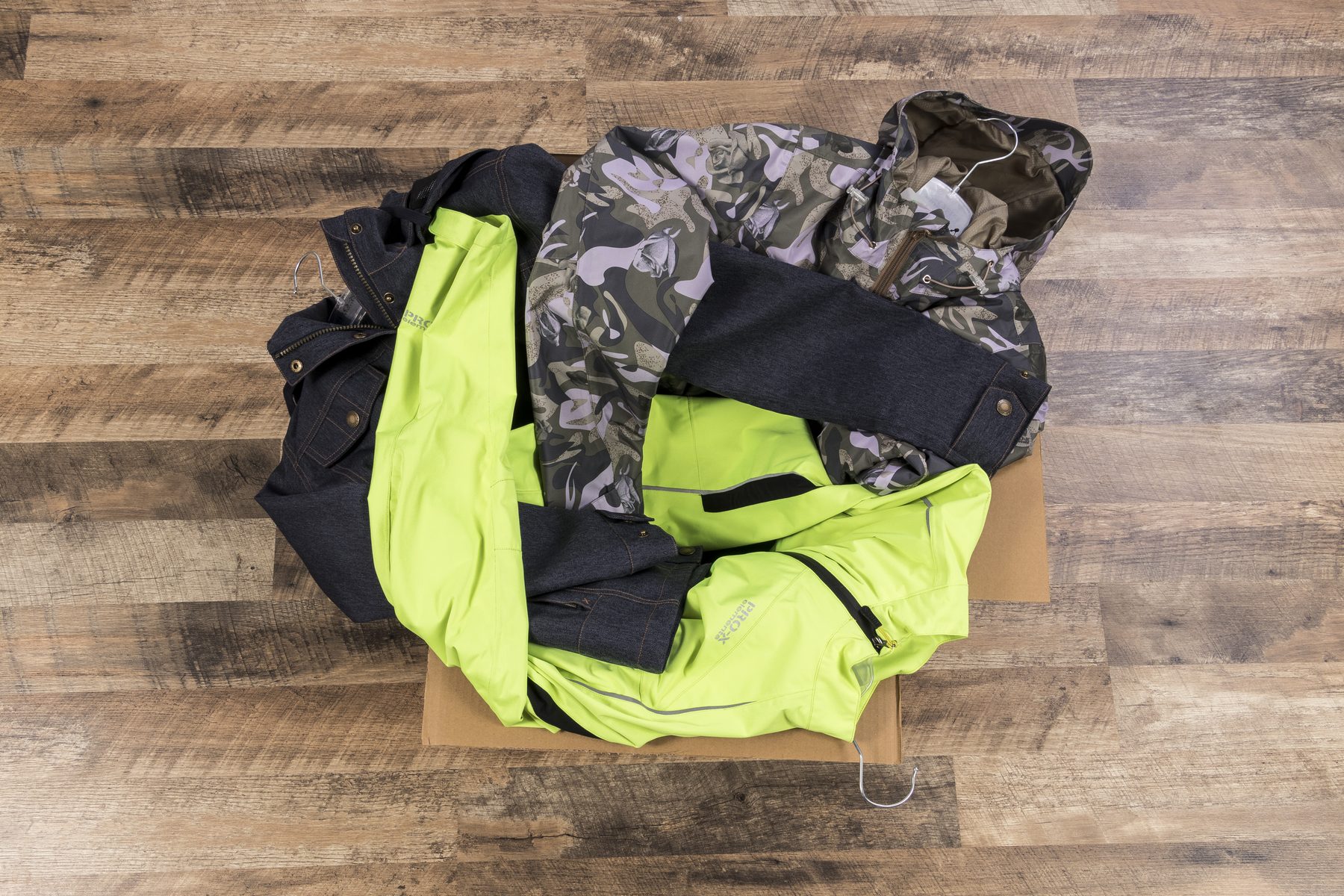 Flat-Lay-Aufnahme mehrerer Jacken auf Holzboden