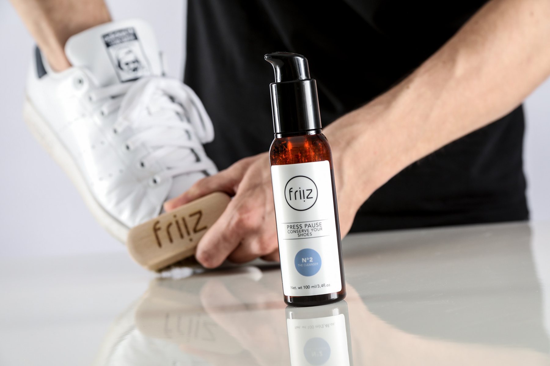 Schuhpflege-Pumpflasche mit Bürste beim Reinigen eines Sneakers