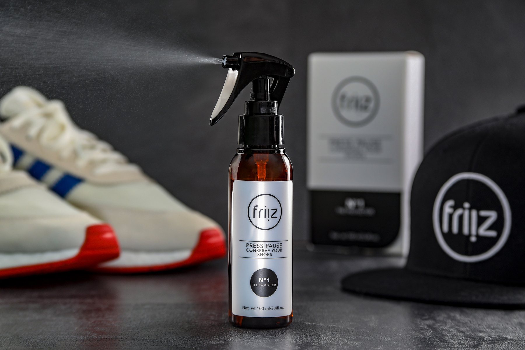 Schuhpflege-Sprühflasche vor Sneaker und Cap