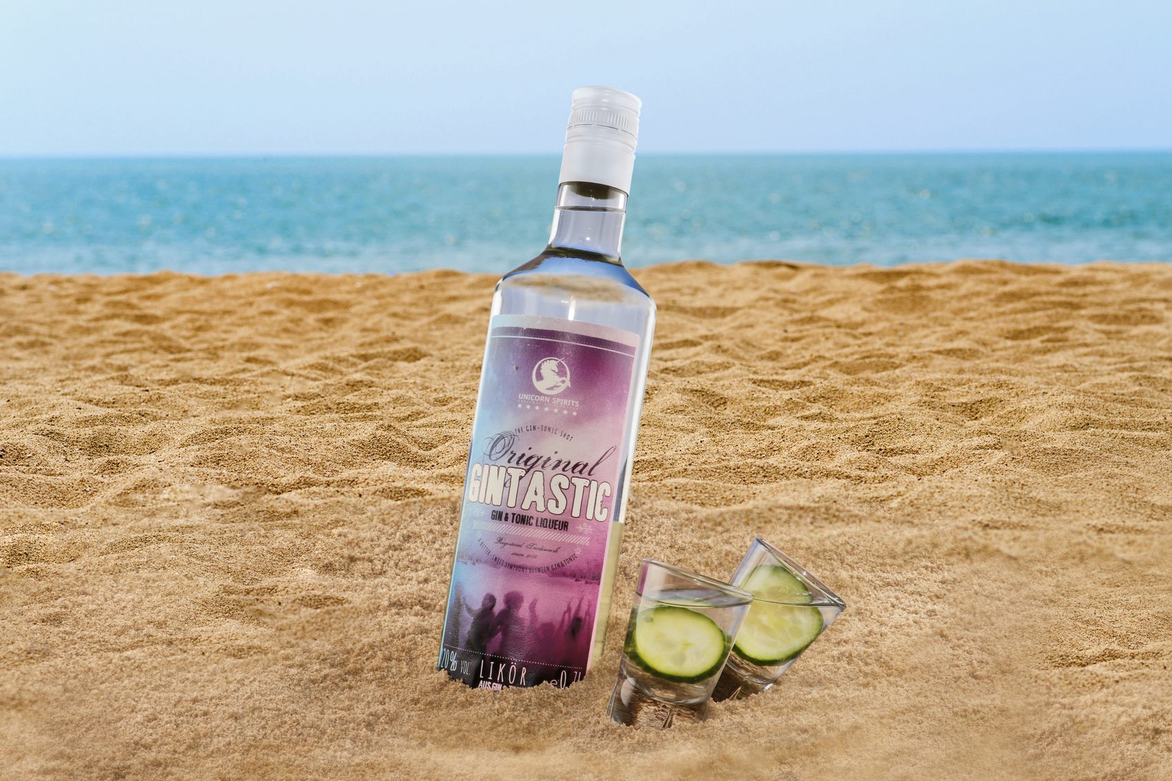 Gin-Tonic-Likörflasche mit zwei Gläsern im Sand am Strand