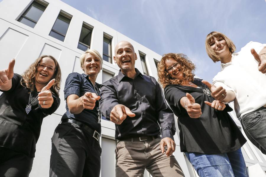 Team zeigt lachend in die Kamera